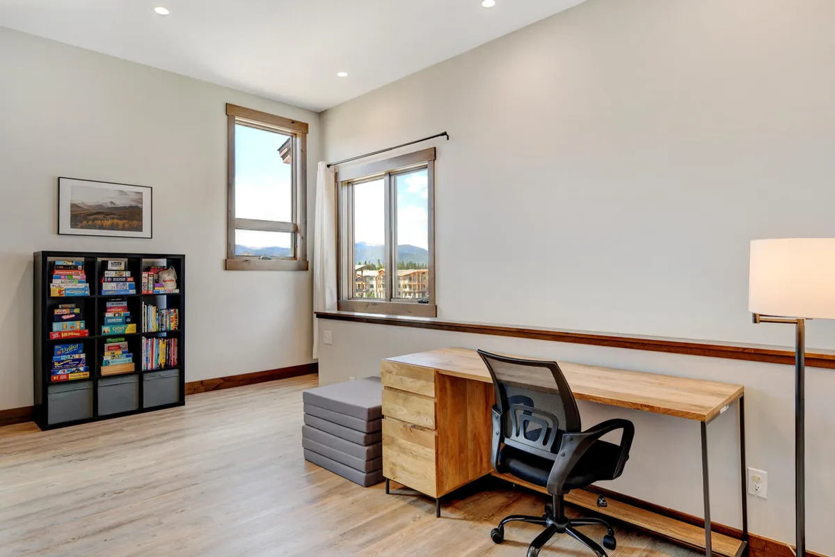 A focused workspace featuring a desk and chair positioned next to a window with a picturesque view. A bookshelf filled with books adds to the ambiance, making this area ideal for remote work, reading, or creative pursuits in a calm setting.
