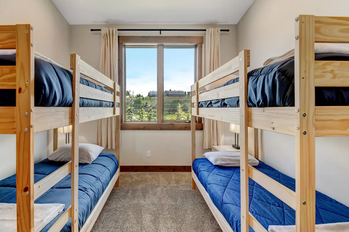 A bright, playful bunk room with sturdy bunk beds, soft bedding, and a large window letting in natural light. The layout is inviting for families or groups, offering a welcoming retreat for younger guests or flexible sleeping arrangements.