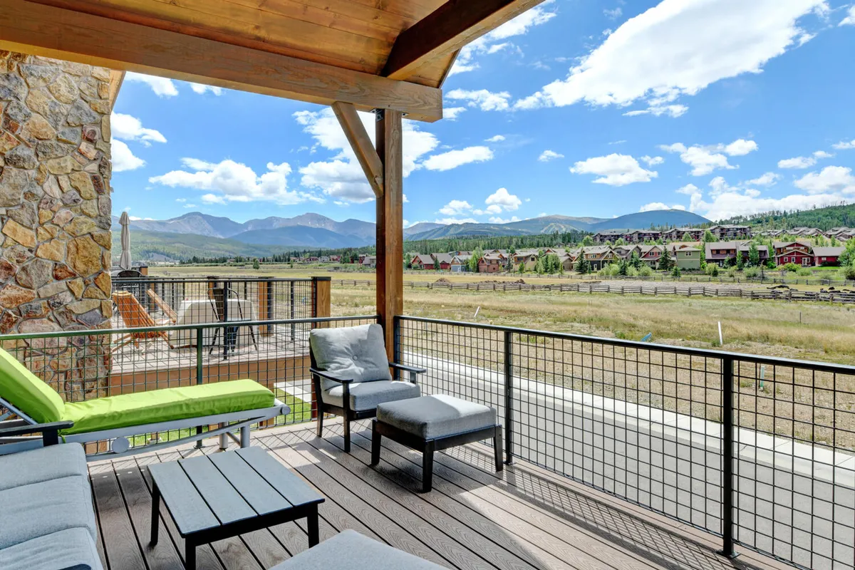A peaceful outdoor view that highlights a wooden deck with outdoor seating, surrounded by natural landscape and mountain views. The setting encourages relaxation, family conversations, and enjoying sunsets or warm summer evenings together.